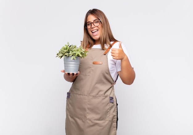 Jeune femme jardinière se sentant fière, insouciante, confiante et heureuse, souriant positivement avec le pouce levé