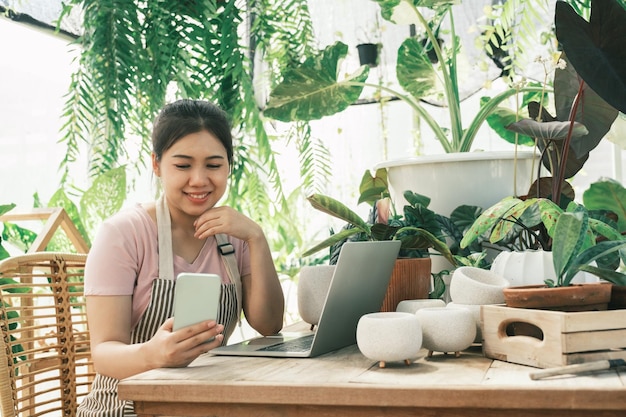 Une jeune femme jardinière se tient dans le jardin pour contacter les clients