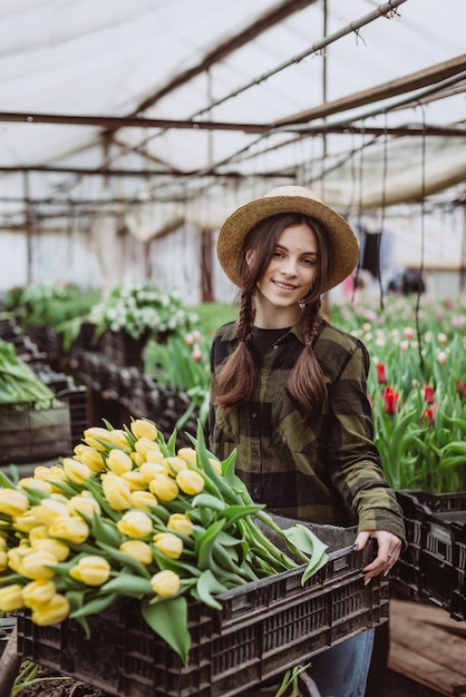 Jeune femme jardinière tient un bouquet de tulipes cultivées dans une serre.