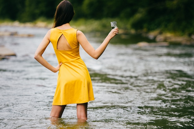 Jeune, femme, jaune, robe, debout, rivière, tenue, verre, eau, main