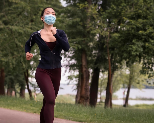 Jeune femme jogging avec masque médical sur
