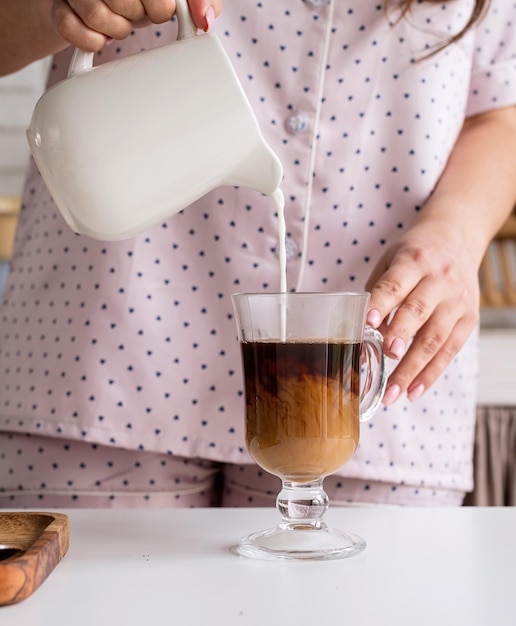 Jeune femme en joli pyjama faisant du café à la cuisine à domicile