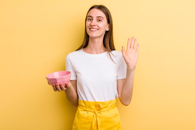 Jeune femme jolie chef adulte avec un bol vide