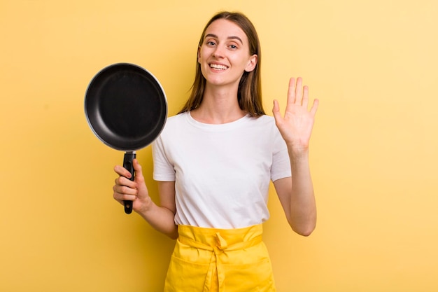 Jeune femme jolie chef adulte avec une casserole