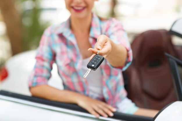 Photo jeune femme jolie debout près de décapotable avec les clés à la main concept d'achat d'une voiture d'occasion ou une voiture de location