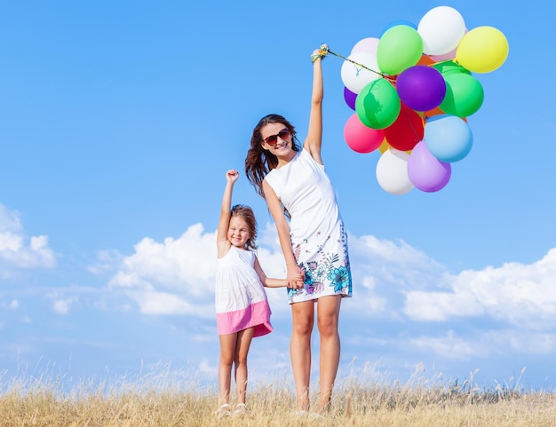 Jeune femme avec une jolie petite fille et des ballons à air colorés