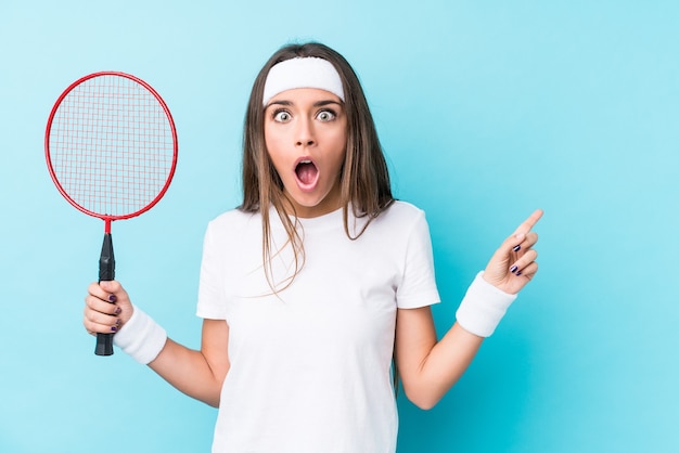 Jeune femme jouant au badminton isolé pointant vers le côté