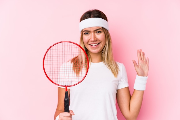 Jeune femme jouant au badminton souriant gai montrant le numéro cinq avec les doigts.