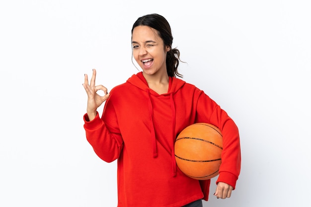 Jeune femme jouant au basket-ball sur fond blanc isolé montrant signe ok avec les doigts