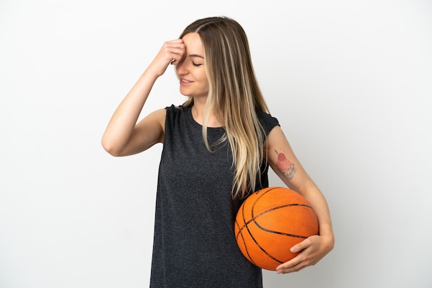 Jeune femme jouant au basket-ball sur un mur blanc isolé en riant