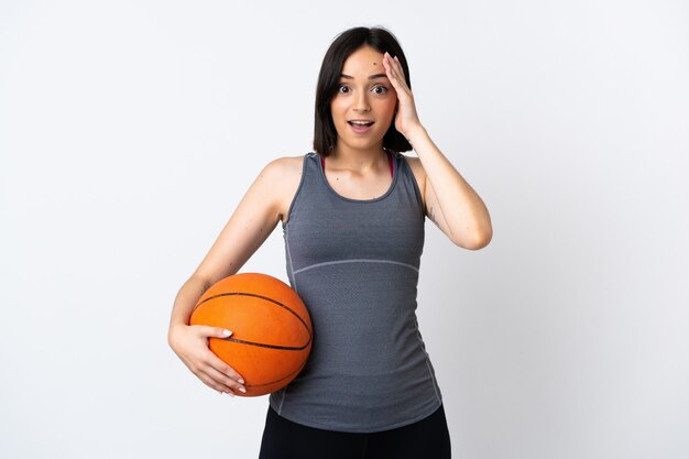 Jeune femme jouant au basket isolé sur blanc avec une expression de surprise