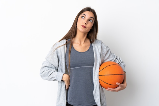 Jeune femme jouant au basket isolé sur fond blanc et levant