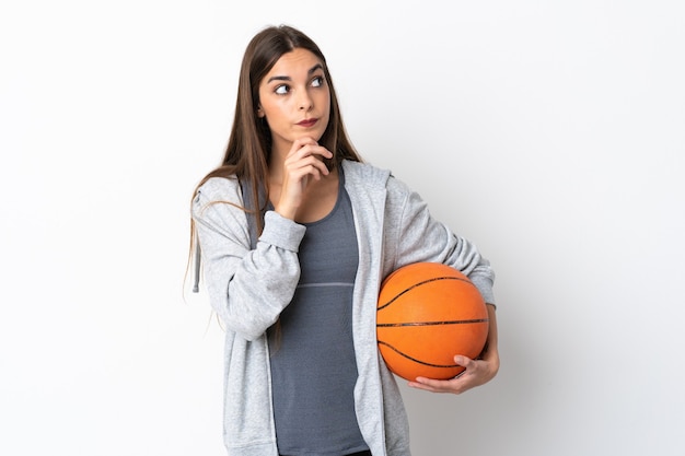 Jeune femme jouant au basket isolé sur fond blanc et levant