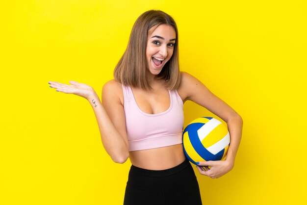 Jeune femme jouant au volley-ball isolé sur fond jaune avec une expression faciale choquée