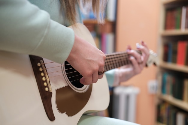 Jeune femme jouant de la guitare acoustique. gros plan sans visage