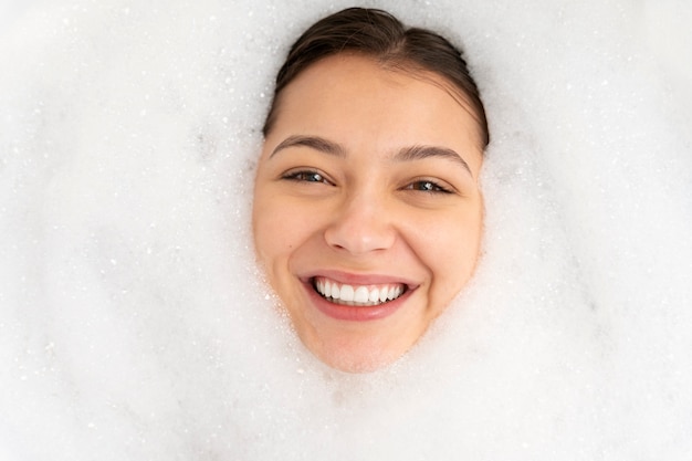 Photo jeune femme jouant avec la mousse en prenant un bain