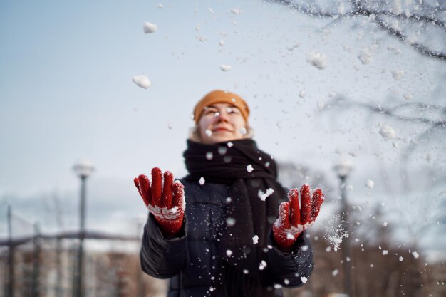 Une jeune femme jouant avec de la neige en hiver.