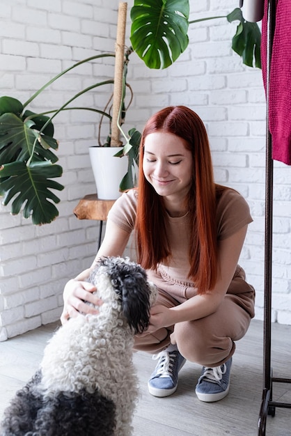 Jeune femme jouant avec son chien mignon à la maison