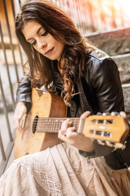 Photo une jeune femme joue de la guitare assise sur les marches.