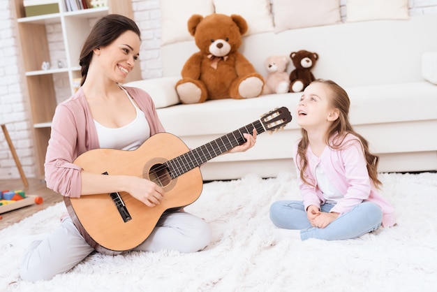 Une jeune femme joue de la guitare et une fille chante.