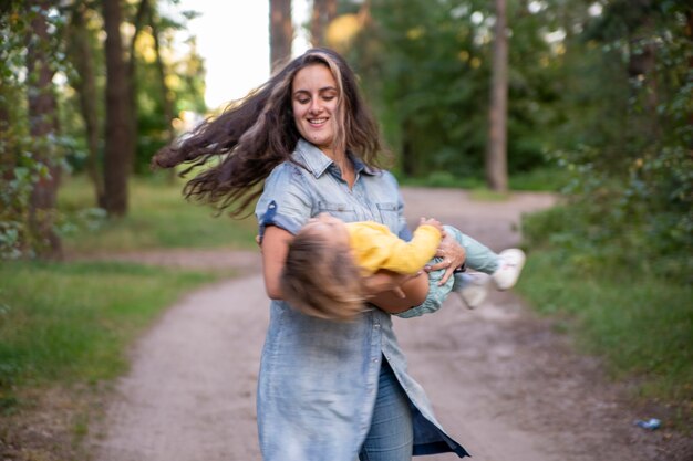 jeune femme joue avec une petite fille en jaune dans le parc.