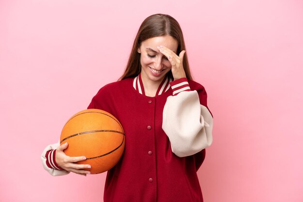 Jeune femme de joueur de basket-ball caucasien sur isolé sur fond rose en riant