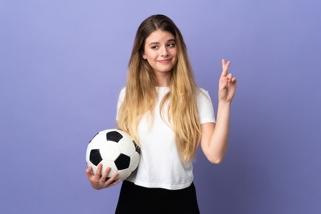 Jeune femme de joueur de football blonde isolée avec les doigts croisés et souhaitant le meilleur