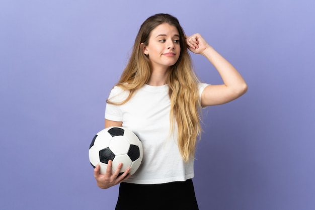 Jeune femme de joueur de football blonde isolée sur l'espace violet ayant des doutes et de la pensée
