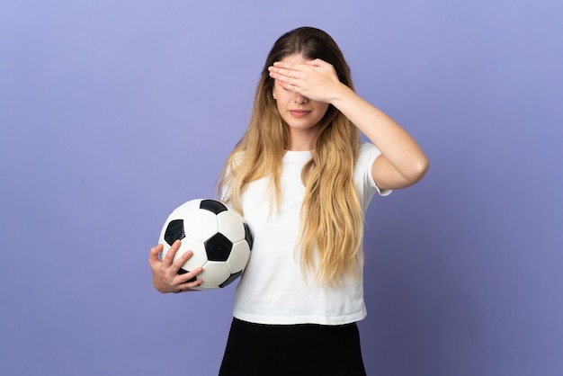 Jeune femme de joueur de football blonde isolée sur le mur violet couvrant les yeux par les mains. Je ne veux pas voir quelque chose