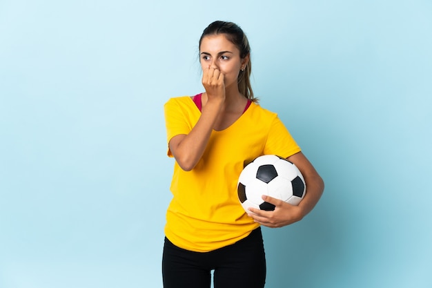 Jeune femme de joueur de football hispanique sur isolé sur bleu ayant des doutes