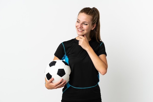 Jeune femme de joueur de football isolée sur un mur blanc regardant sur le côté et souriant