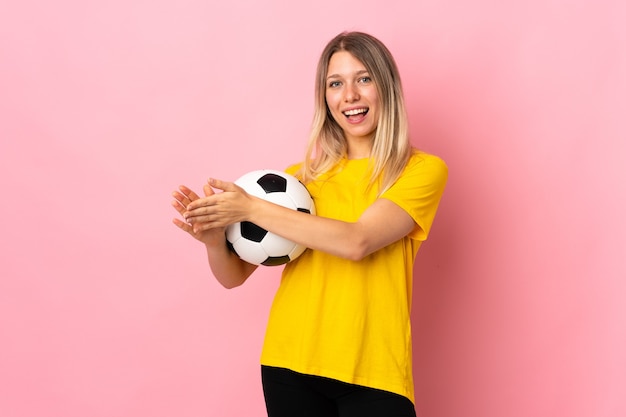 Jeune femme de joueur de football isolée sur mur rose applaudissant