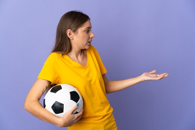 Jeune femme joueur de football lituanien isolé sur fond violet avec une expression de surprise tout en regardant côté