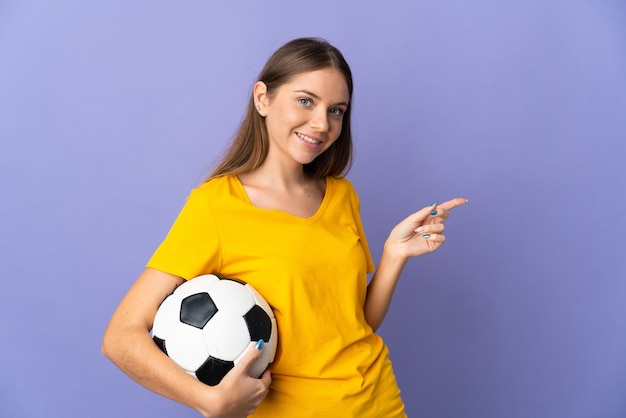 Jeune femme joueur de football lituanien isolé sur mur violet doigt pointé sur le côté