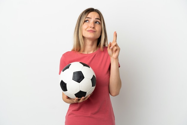 Jeune femme de joueur de football sur un mur blanc isolé avec les doigts croisés et souhaitant le meilleur