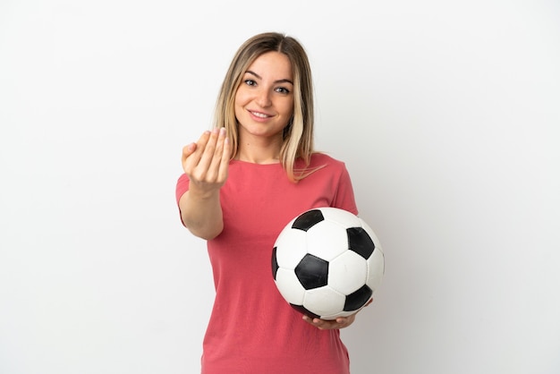 Jeune femme de joueur de football sur un mur blanc isolé invitant à venir avec la main. Heureux que tu sois venu