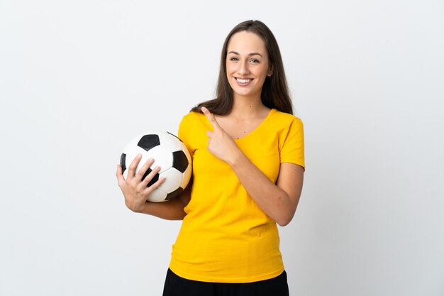 Jeune femme de joueur de football sur un mur blanc isolé pointant vers le côté pour présenter un produit