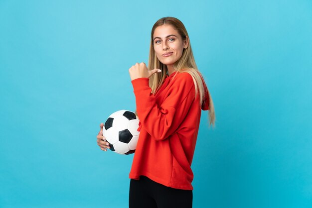 Jeune femme de joueur de football posant isolé contre le mur blanc