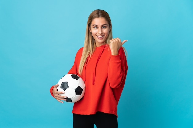 Jeune femme de joueur de football posant isolé contre le mur blanc