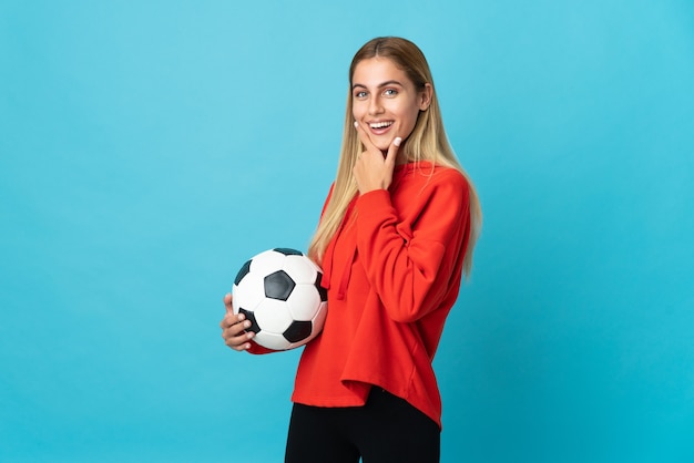 Jeune femme de joueur de football posant isolé contre le mur blanc