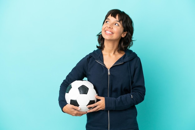 Jeune femme de joueur de football de race mixte isolée sur fond bleu pensant à une idée tout en levant les yeux