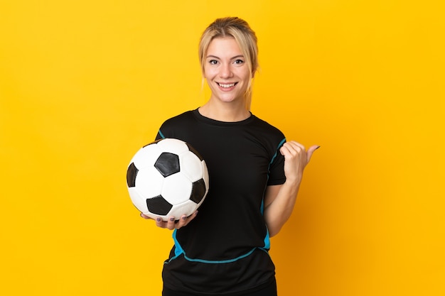 Jeune femme de joueur de football russe isolée sur fond jaune pointant vers le côté pour présenter un produit