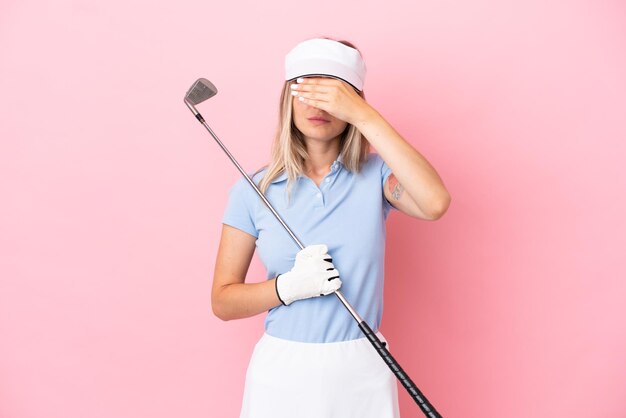 Jeune femme de joueur de golfeur isolée sur fond rose couvrant les yeux par les mains. Je ne veux pas voir quelque chose