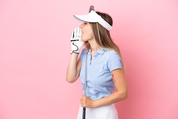 Jeune femme de joueur de golfeur isolée sur fond rose criant avec la bouche grande ouverte sur le côté