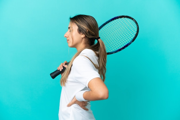 Jeune femme joueur de tennis isolé sur fond bleu souffrant de maux de dos pour avoir fait un effort