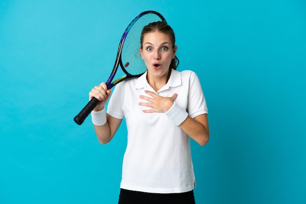 Jeune femme joueur de tennis isolé sur fond bleu surpris et choqué tout en regardant à droite