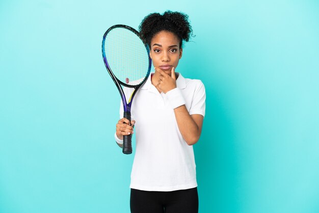 Jeune femme de joueur de tennis isolée sur fond bleu pensant