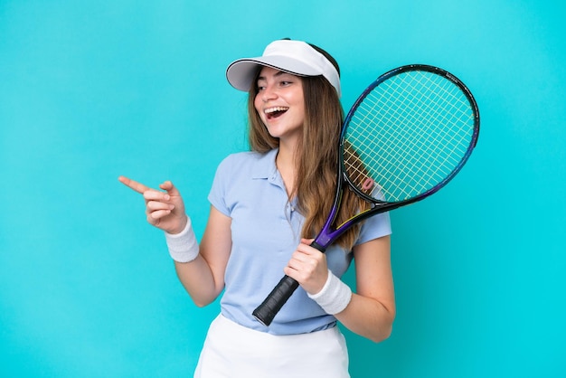 Jeune femme de joueur de tennis isolée sur fond bleu, pointant le doigt sur le côté et présentant un produit