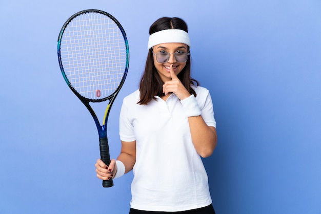 Jeune femme joueuse de tennis sur le mur montrant un signe de silence mettant le doigt dans la bouche