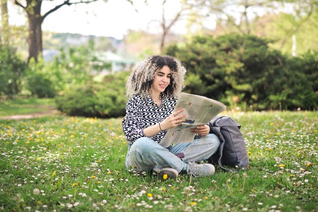 jeune femme avec un journal dans un parc